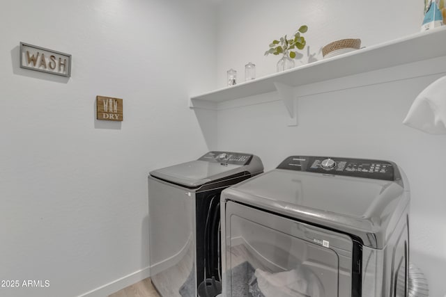 laundry area with laundry area, washer and clothes dryer, light wood-style flooring, and baseboards