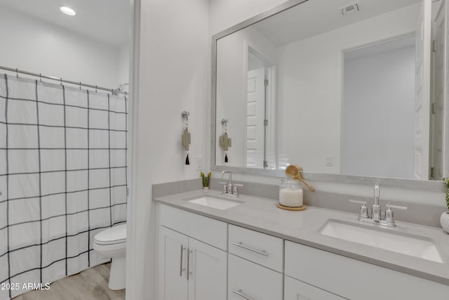 bathroom featuring visible vents, a sink, toilet, and double vanity