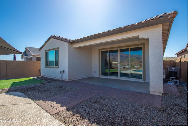 rear view of house featuring a tiled roof, a patio area, fence, and stucco siding