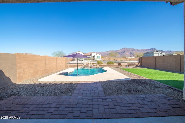 view of swimming pool featuring a fenced in pool, a yard, a patio area, a mountain view, and a fenced backyard