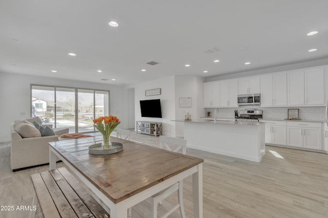 kitchen with tasteful backsplash, recessed lighting, appliances with stainless steel finishes, light wood-style floors, and open floor plan