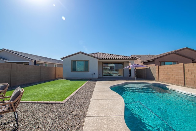 back of house featuring a fenced in pool, a fenced backyard, a tiled roof, a patio area, and stucco siding