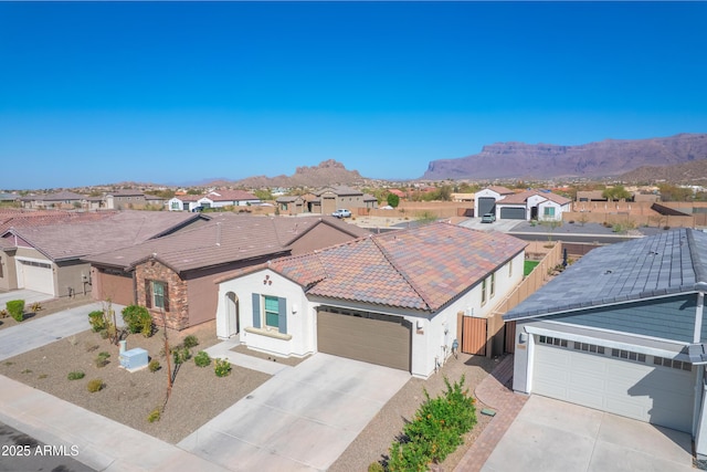 view of front facade featuring concrete driveway, a tile roof, a residential view, an attached garage, and a mountain view