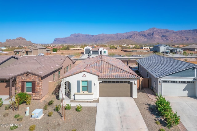 view of front of property with a tile roof, stucco siding, concrete driveway, a mountain view, and a garage