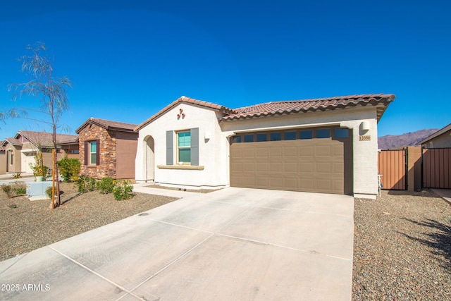 mediterranean / spanish home with stucco siding, concrete driveway, an attached garage, stone siding, and a tiled roof