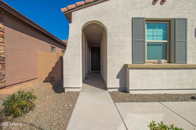 doorway to property with fence and stucco siding