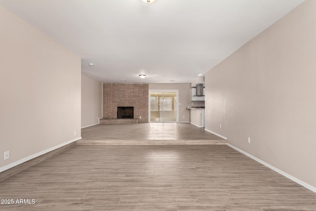 9803 N 40th Dr, Phoenix, AZ 85051 - unfurnished living room with baseboards, a brick fireplace, and wood finished floors