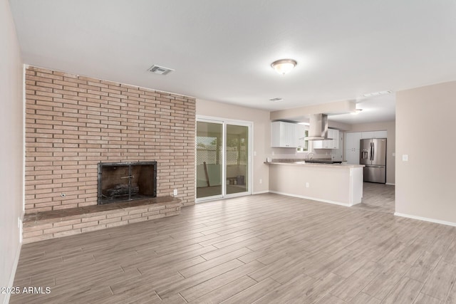 9803 N 40th Dr, Phoenix, AZ 85051 - unfurnished living room featuring a brick fireplace, light wood-style floors, and baseboards