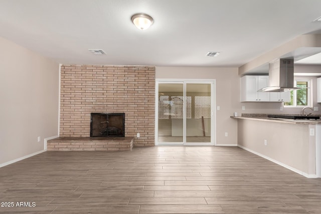 9803 N 40th Dr, Phoenix, AZ 85051 - unfurnished living room featuring wood finished floors, a sink, baseboards, and a brick fireplace