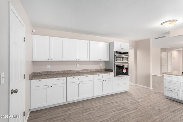 9803 N 40th Dr, Phoenix, AZ 85051 - kitchen featuring stainless steel double oven, light wood-style floors, baseboards, and white cabinetry