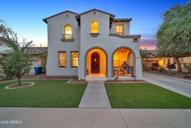 mediterranean / spanish-style home with a yard and covered porch