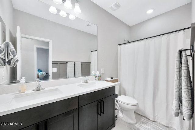 bathroom with toilet, vanity, and tile patterned flooring