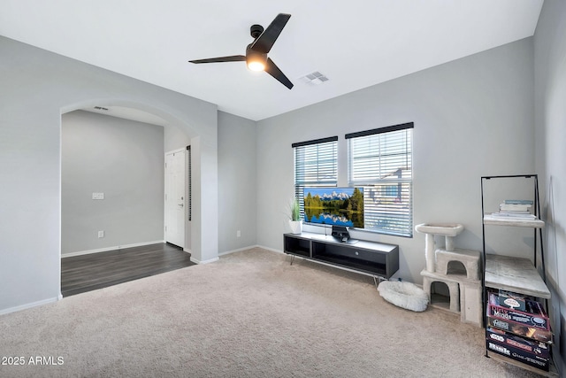 living area featuring ceiling fan and dark colored carpet