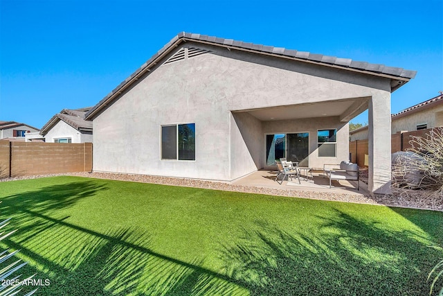 back of property with a lawn and a patio