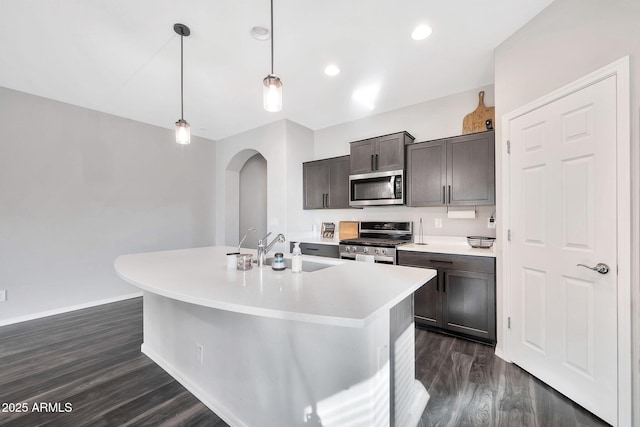 kitchen featuring sink, hanging light fixtures, an island with sink, stainless steel appliances, and dark hardwood / wood-style flooring