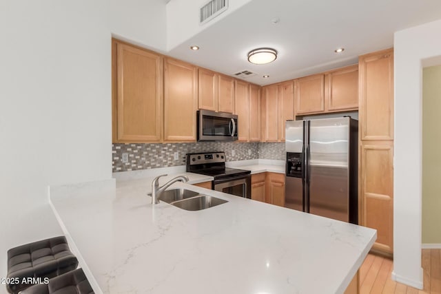 kitchen featuring a sink, stainless steel appliances, a peninsula, and light brown cabinets