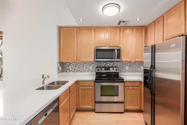 kitchen with a sink, stainless steel appliances, decorative backsplash, and light countertops