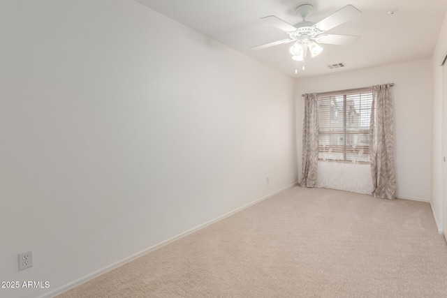 spare room featuring ceiling fan, light colored carpet, visible vents, and baseboards