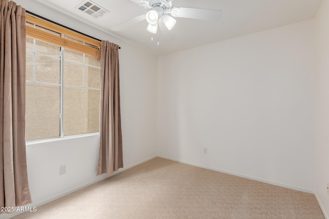 carpeted spare room with a ceiling fan, visible vents, and baseboards