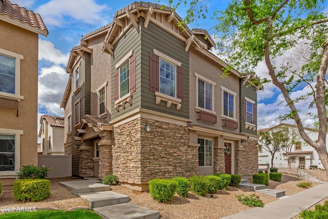 view of front facade with stone siding, stucco siding, and fence