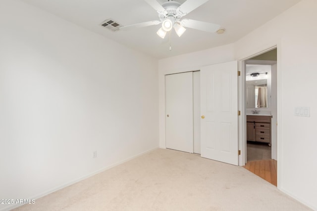 unfurnished bedroom with visible vents, a sink, ceiling fan, a closet, and light carpet