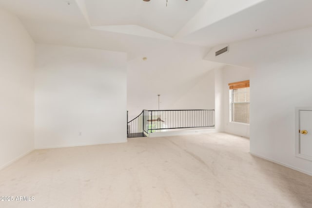 carpeted spare room with visible vents, baseboards, a ceiling fan, and vaulted ceiling