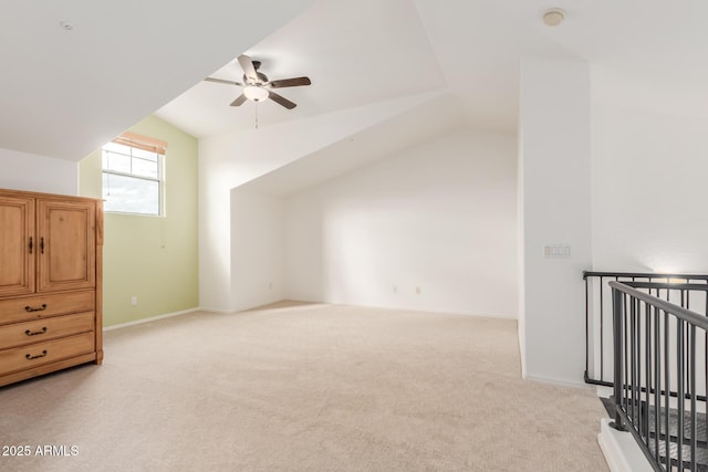 additional living space featuring light colored carpet, ceiling fan, baseboards, and vaulted ceiling