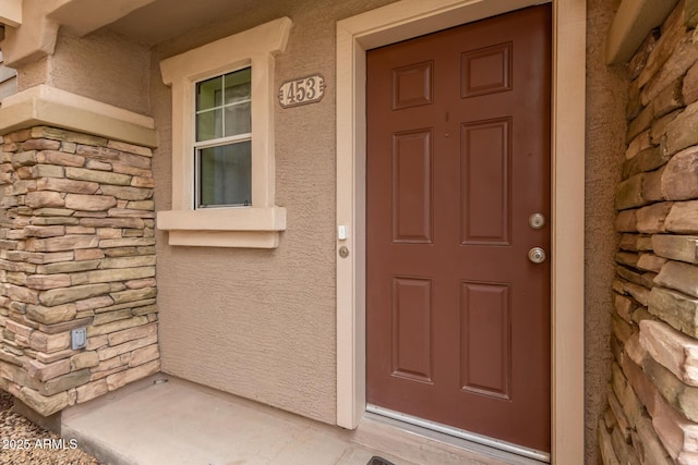 entrance to property featuring stone siding and stucco siding