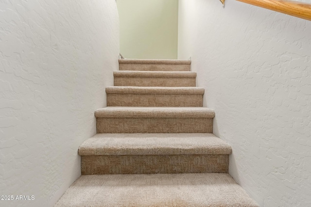 stairs featuring carpet flooring and a textured wall