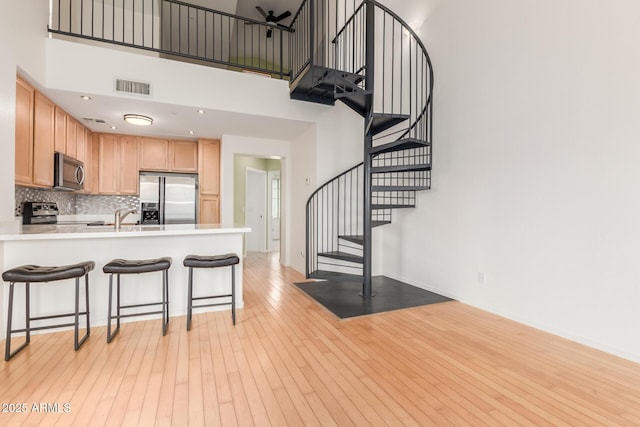 kitchen with visible vents, backsplash, light wood-style flooring, appliances with stainless steel finishes, and a peninsula