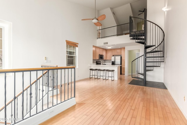 interior space featuring stairs, baseboards, light wood-style floors, and a ceiling fan