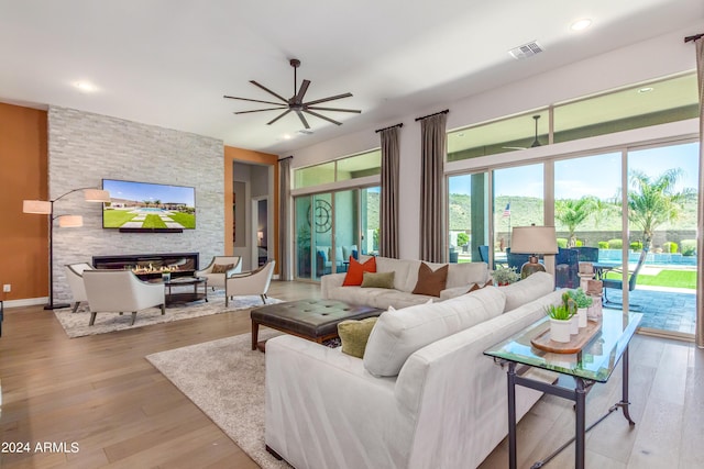 living room featuring a fireplace, light hardwood / wood-style flooring, and ceiling fan