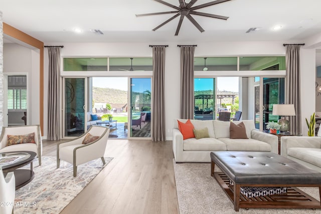 living room with a mountain view, light hardwood / wood-style flooring, and ceiling fan