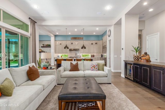 living room with light wood-type flooring, beverage cooler, and sink