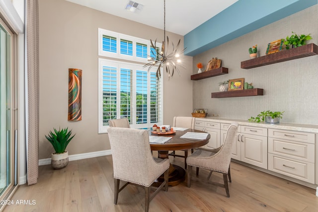 dining area with light hardwood / wood-style flooring and a notable chandelier