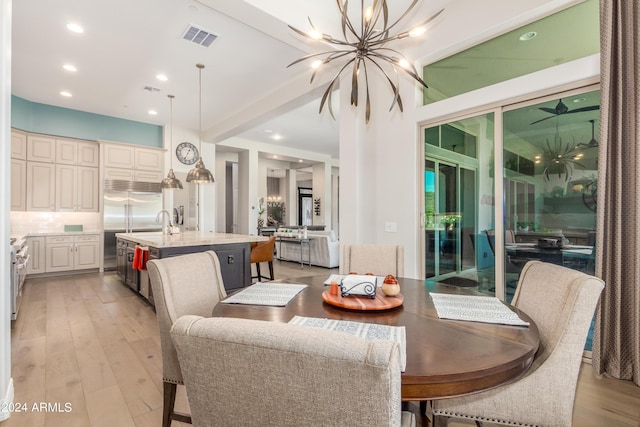 dining room featuring sink, light wood-type flooring, and an inviting chandelier