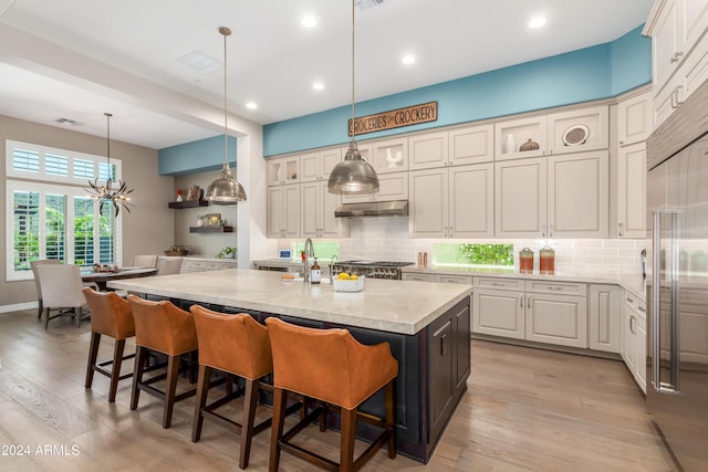 kitchen with backsplash, a kitchen island with sink, a breakfast bar, and light wood-type flooring