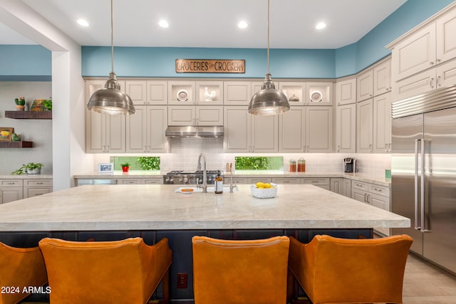 kitchen featuring a kitchen bar, built in refrigerator, and an island with sink