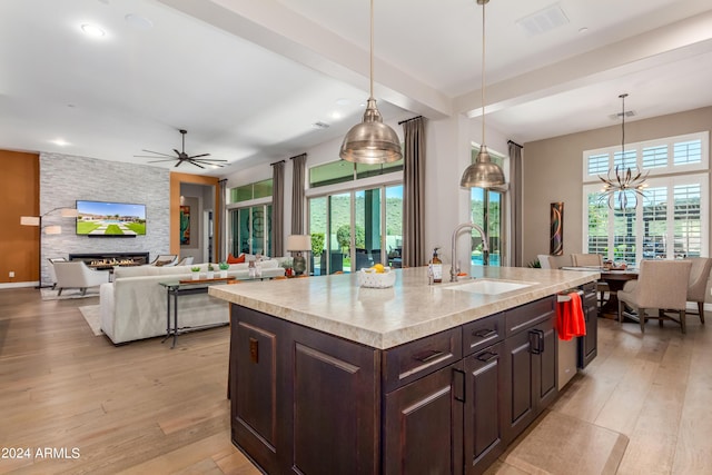 kitchen with ceiling fan with notable chandelier, a kitchen island with sink, sink, hanging light fixtures, and plenty of natural light