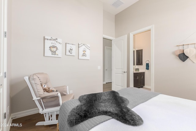 bedroom with ensuite bathroom and dark hardwood / wood-style flooring