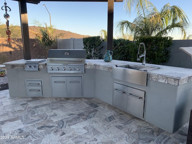 view of patio featuring an outdoor kitchen, area for grilling, and sink