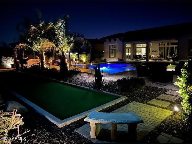 pool at night featuring a patio area