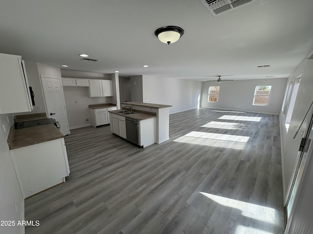 kitchen with white cabinetry, sink, stainless steel dishwasher, an island with sink, and hardwood / wood-style flooring