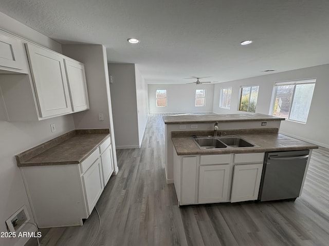 kitchen featuring ceiling fan, sink, dark wood-type flooring, stainless steel dishwasher, and white cabinets