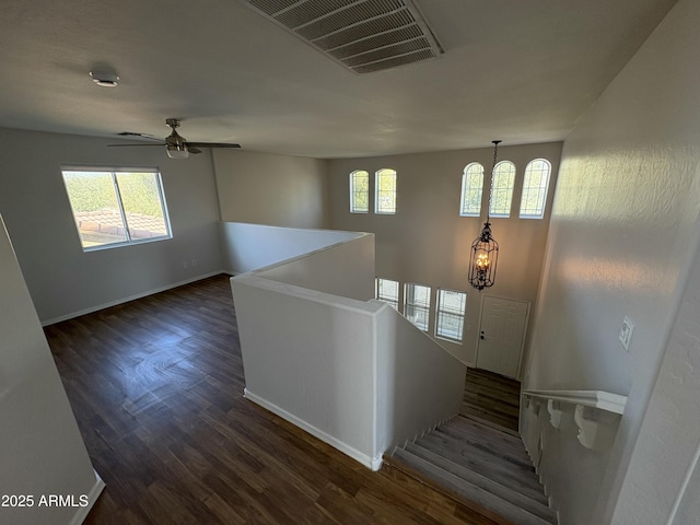 foyer with ceiling fan with notable chandelier and dark hardwood / wood-style flooring