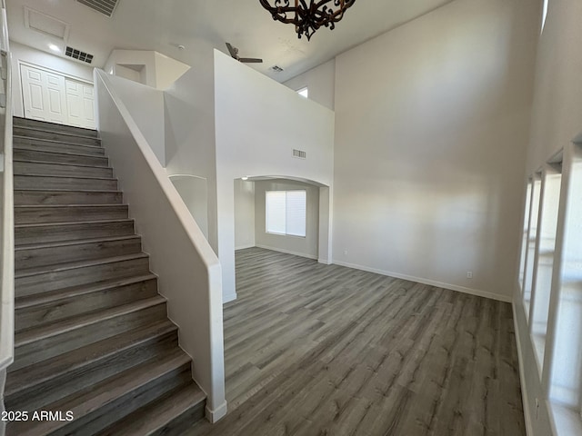 staircase with a wealth of natural light, an inviting chandelier, a high ceiling, and hardwood / wood-style flooring