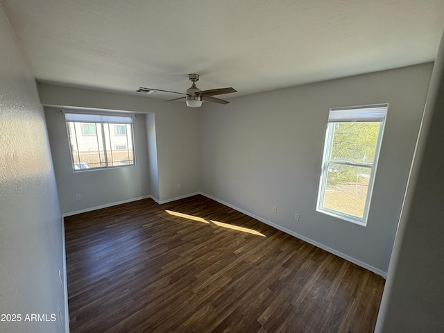 empty room with ceiling fan, a healthy amount of sunlight, and dark hardwood / wood-style flooring