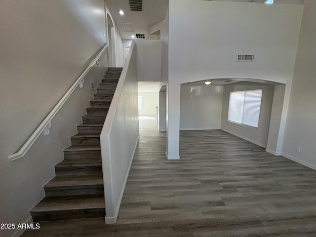 stairs with hardwood / wood-style flooring and a towering ceiling