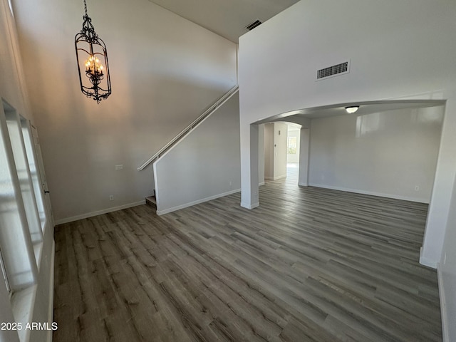 interior space with a towering ceiling, dark wood-type flooring, and an inviting chandelier