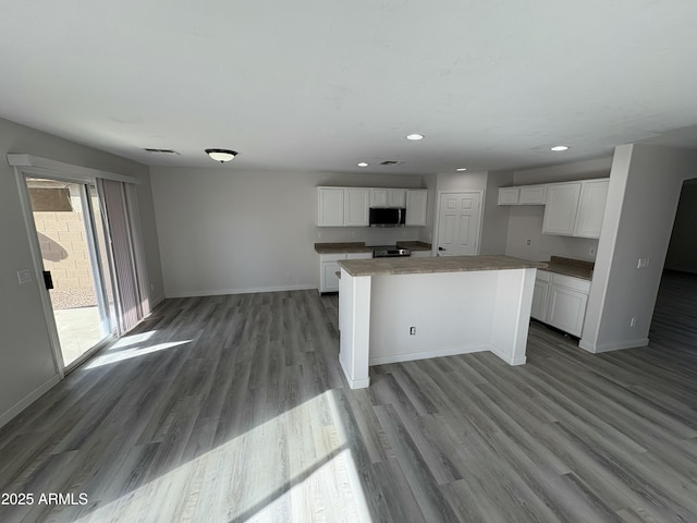 kitchen with white cabinets, a kitchen island, range, and light hardwood / wood-style flooring